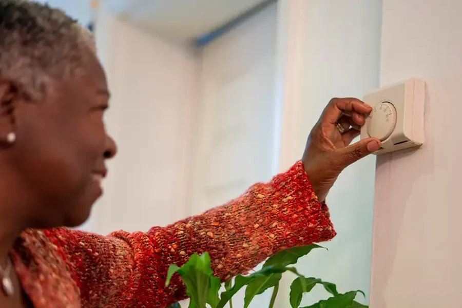 Woman adjusting thermostat at home